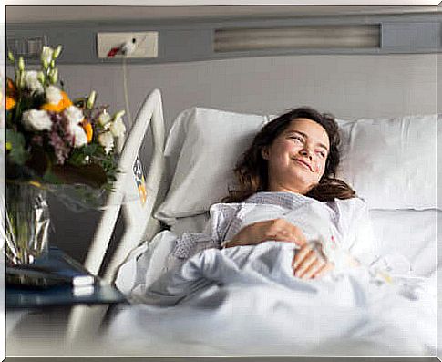 Woman smiling in hospital bed despite illness.