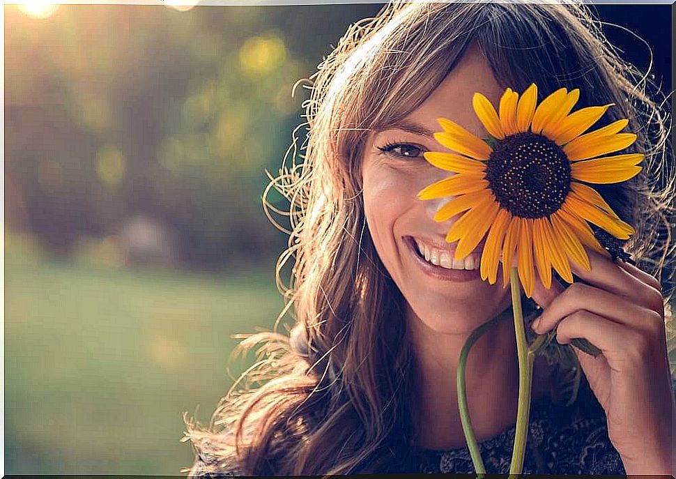 Woman with sunflower in front of her face.