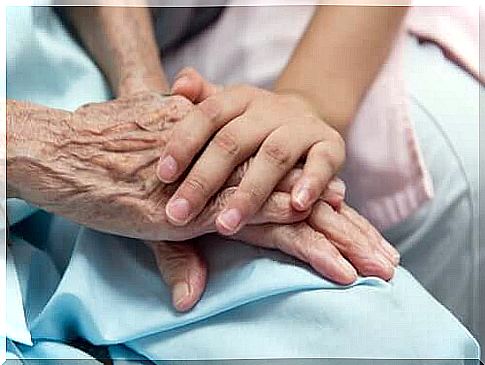 Elderly hand held by young man's hand.