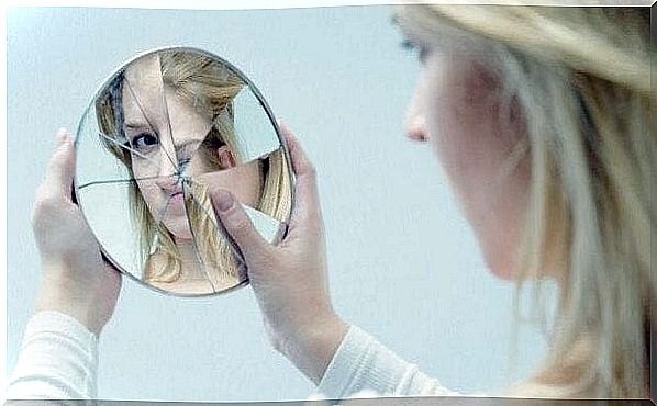 woman looking at herself in broken mirror