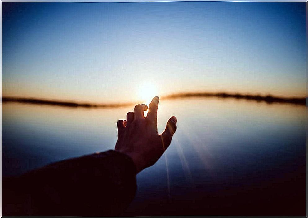 hand trying to catch the sun on the horizon